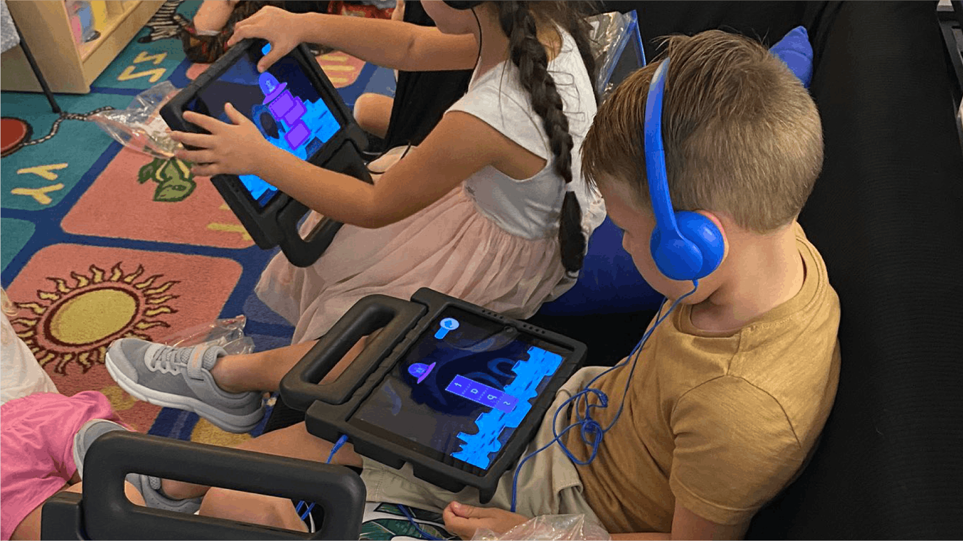 A child with headphones plays a phonics game on the iPad