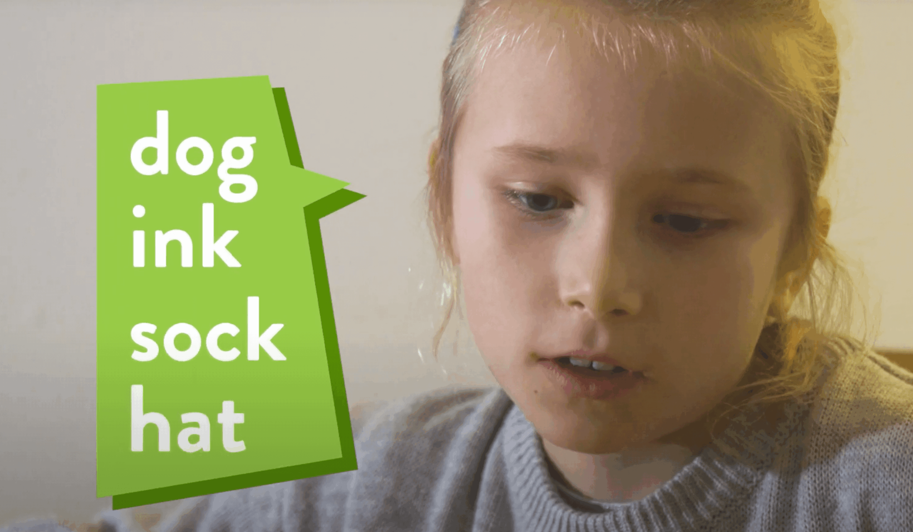 A girl reads dog, ink, sock, hat out loud