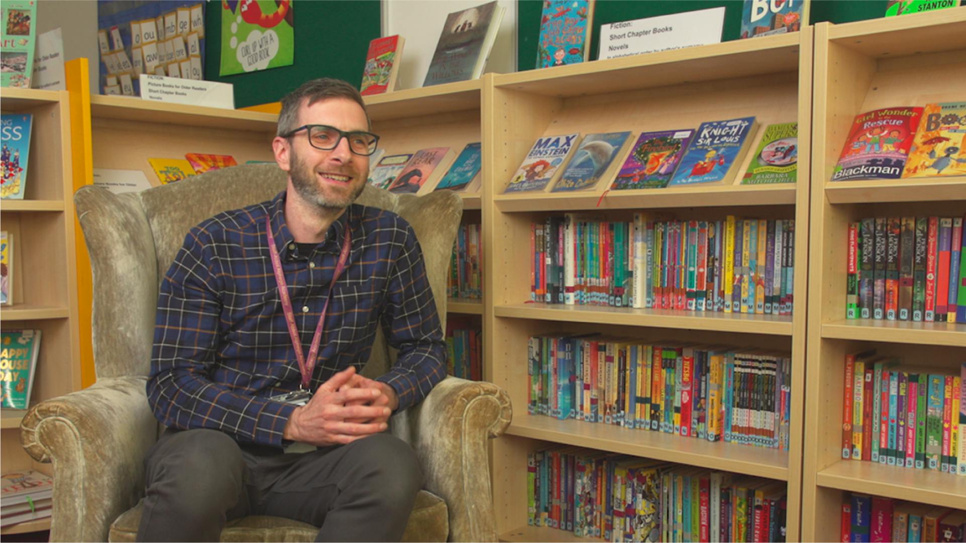 Adam Samuel sitting in front of a full bookshelf