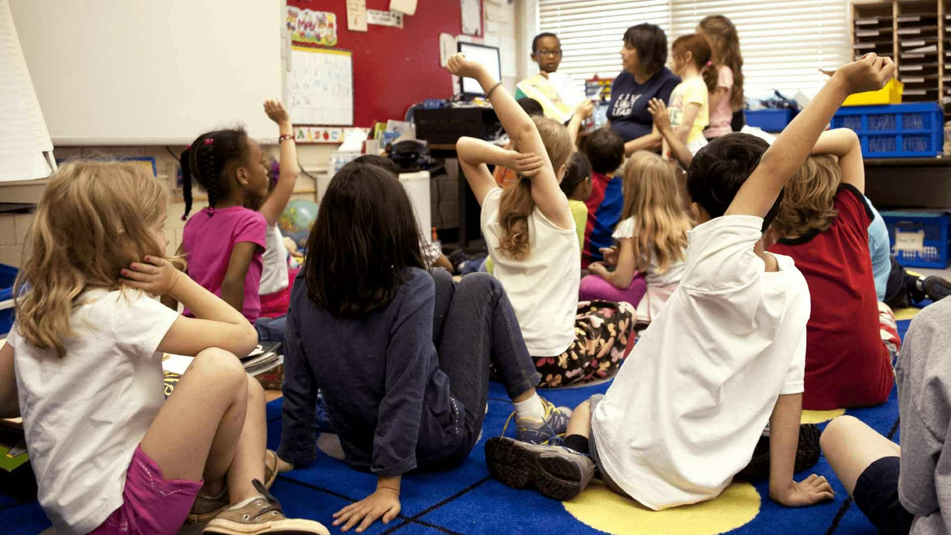 Children on the carpet, some with their hands up