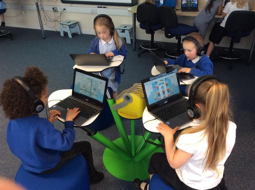 Four students sitting and playing the game on laptops