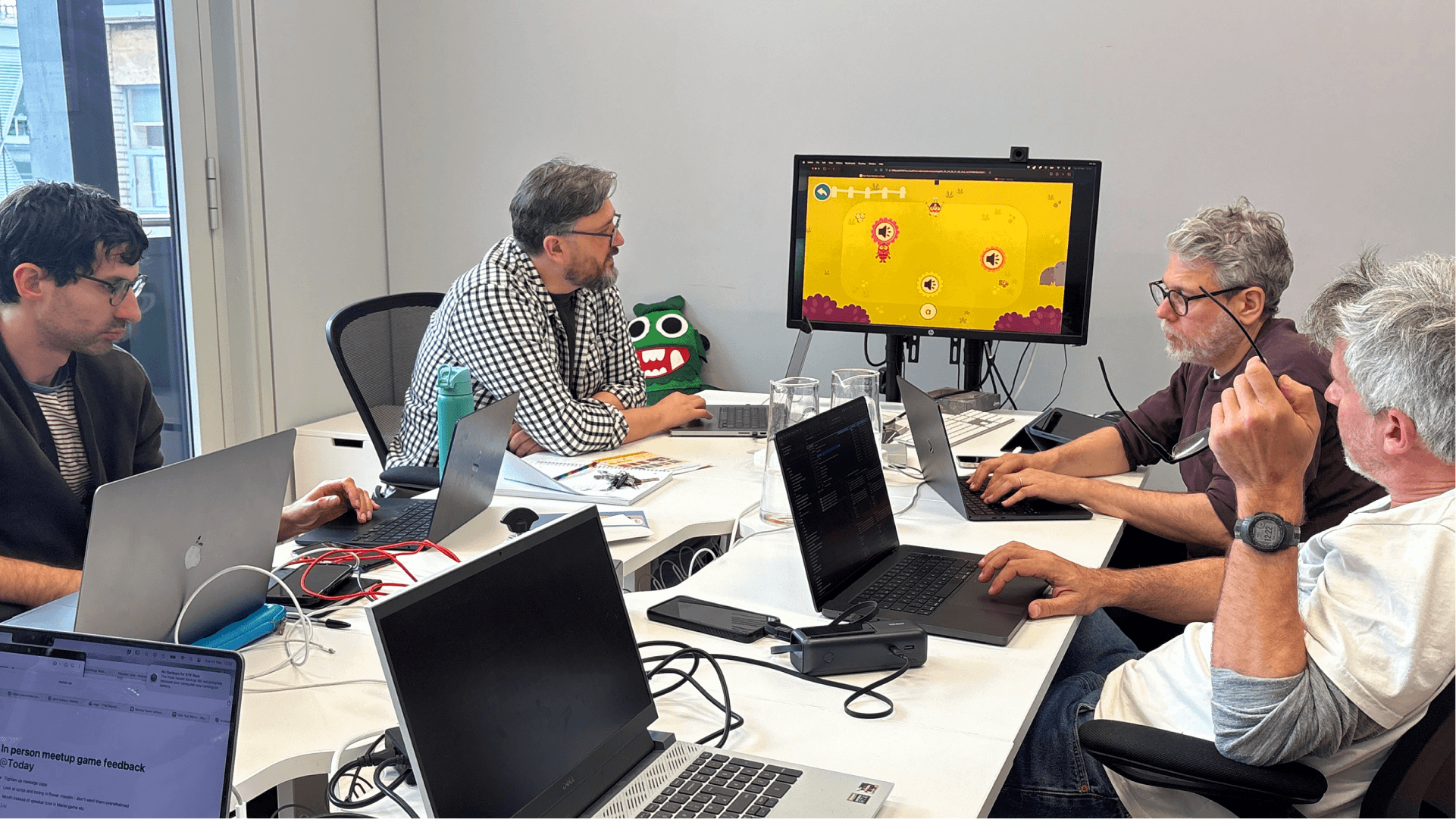 Four game developers gathered around a screen, discussing the game. 