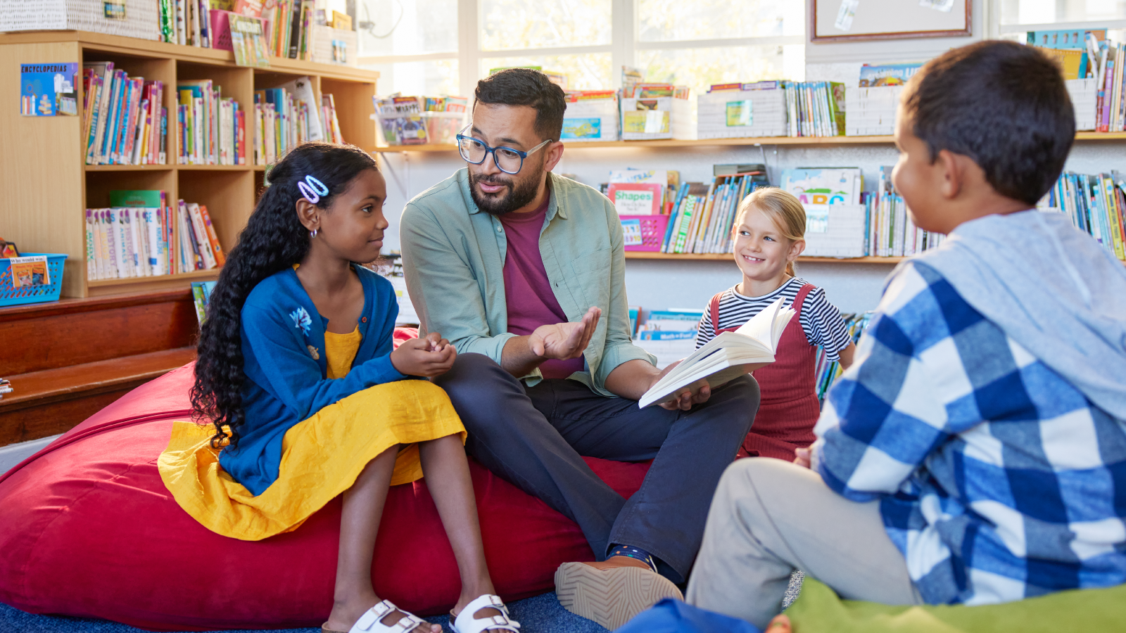 A teacher reads to a pupil in a school library.