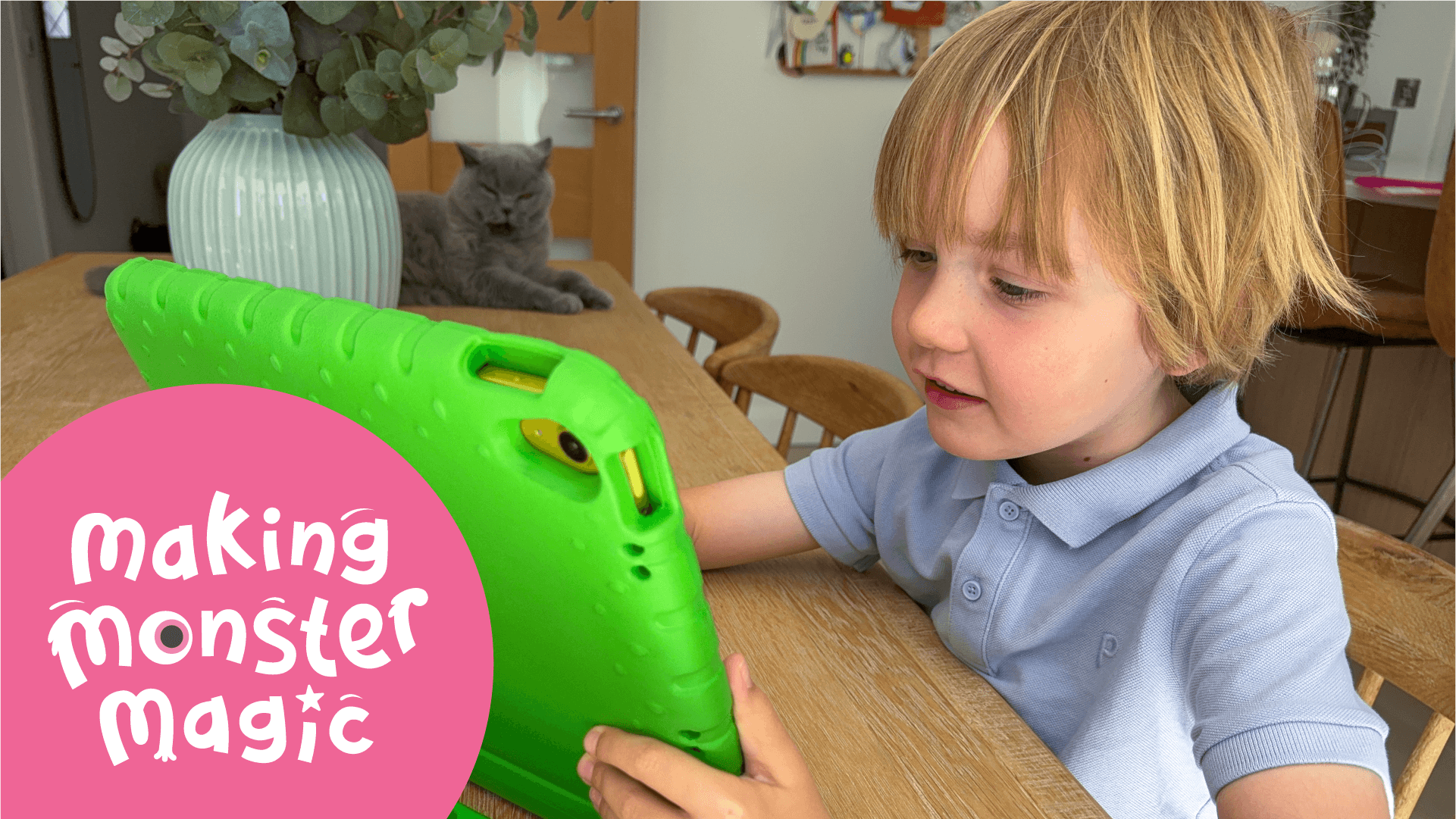 A boy plays on a green iPad, his cat watches him.